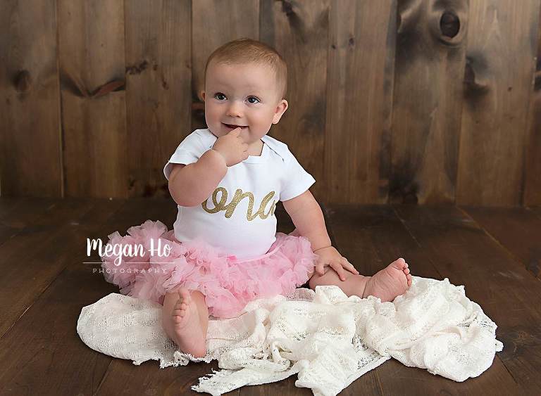 adorable little one year old sitting in pink tutu on wood floor