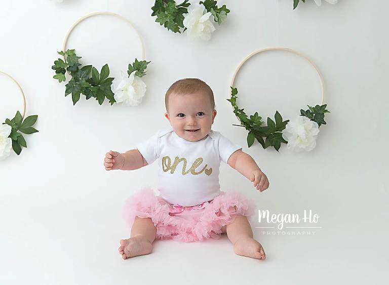 cutest little girl in one year session with floral hoops on white backdrop