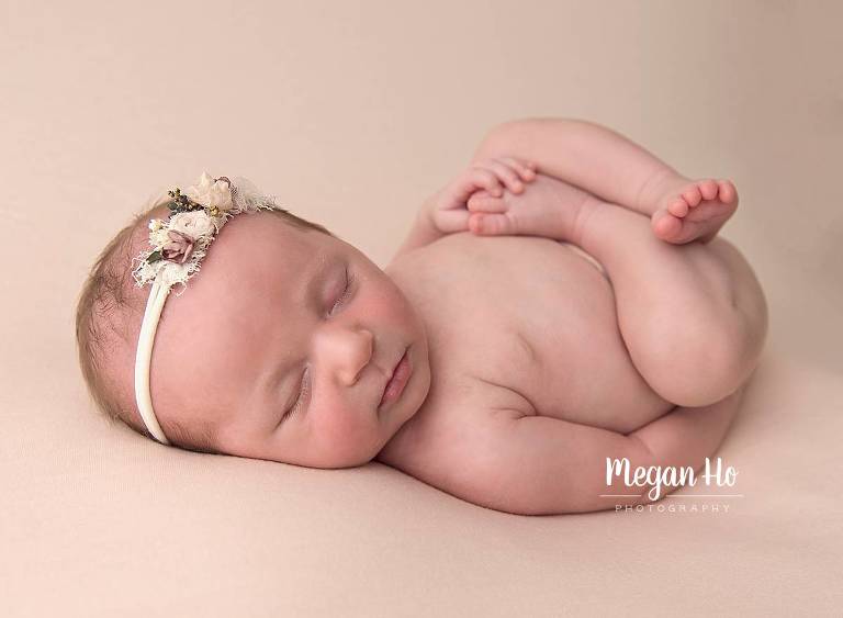 suck finn pose of baby girl in adorable headband sleeping on pink fabric on back