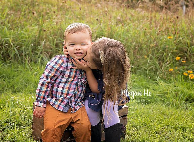 big sister giving brother in plaid shirt a big kiss on cheek