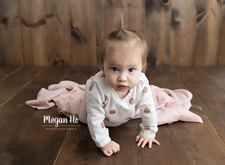 baby girl in polka dots crawling on wood floor