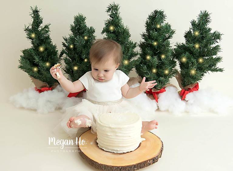 baby girl with icing on toes in adorable Christmas tree cakesmash session