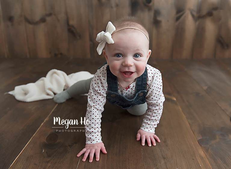 adorable girl in jumpers crawling across wood floor