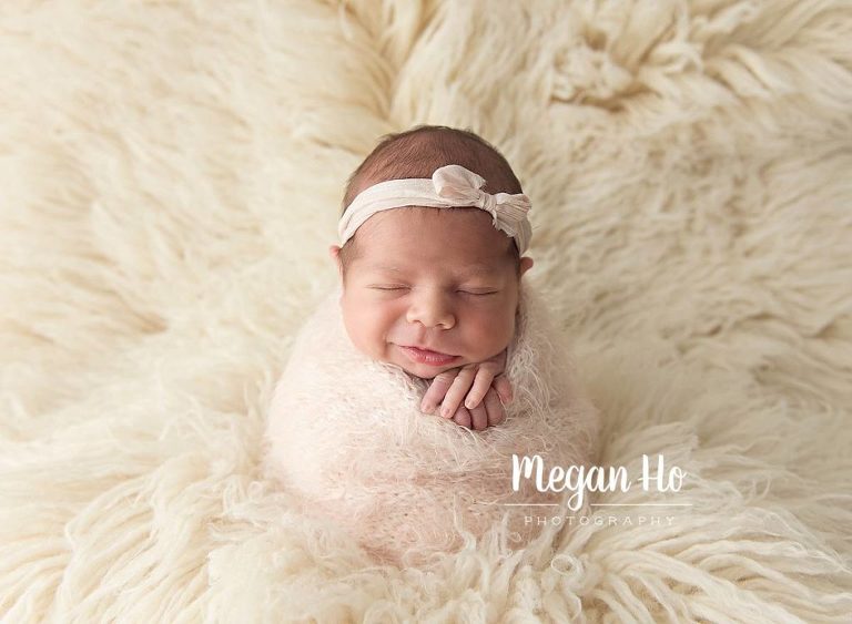 sweetest little girl in potato sack pose smiling on white rug