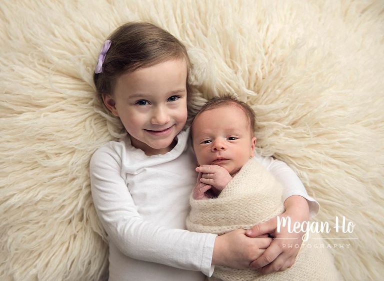 little boy wrapped up snuggling with big sister in newborn session