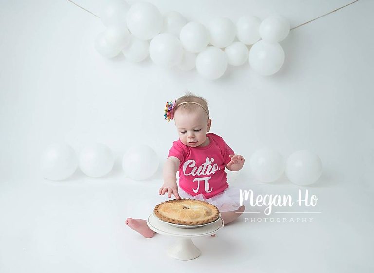 Happy little girl on white background in cutie pie pink shirt in pie smash