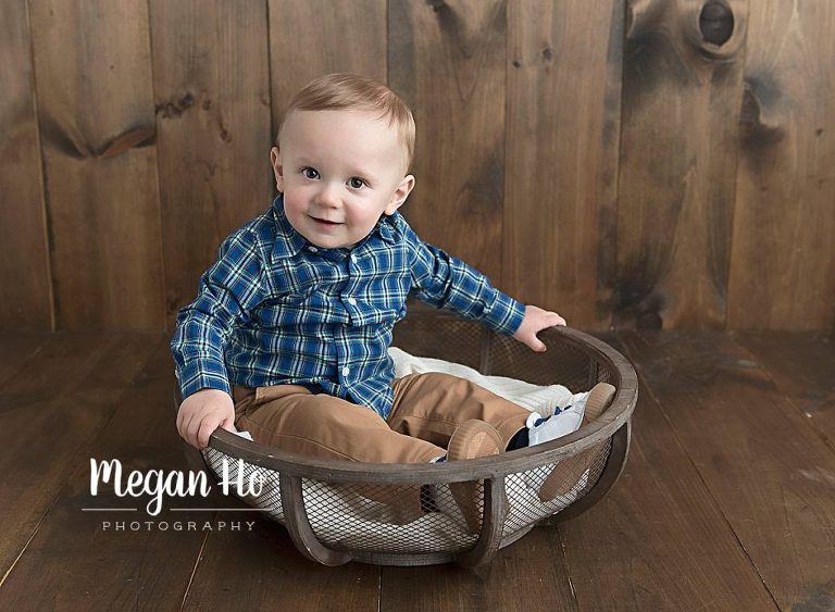 little boy in plaid shirt sitting in wood bowl