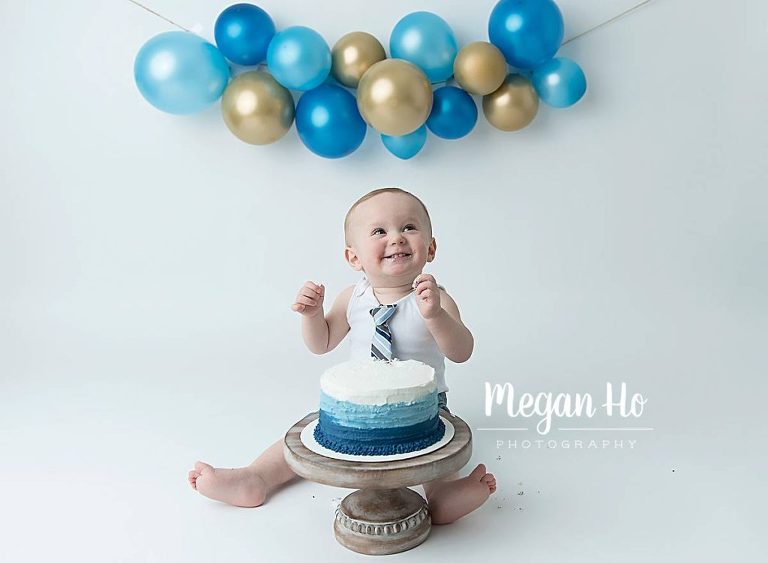 happy little boy about to smash blue and white cake in nh session