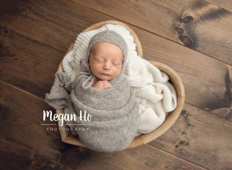 beautiful baby boy in grey knits sleeping in a wooded heart bowl