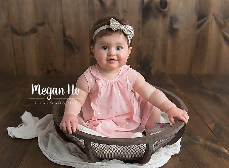 adorable baby girl with gold bow in hear sitting in a bowl in southern nh studio