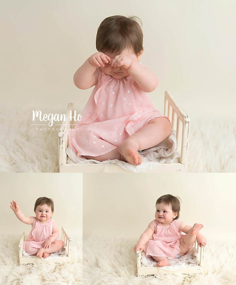 sweet little girl in pink dress sitting on little white bed in one year session