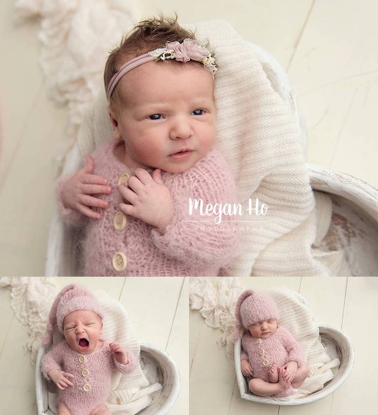 yawning baby girl in pink knit outfit in white heart wooden bowl