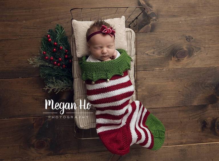Newborn girl born in December sweetly sleeping in a red and green stocking