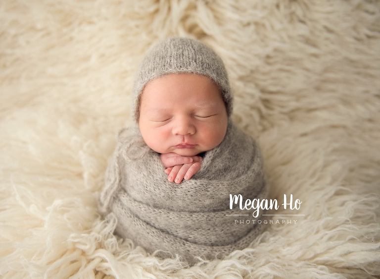 perfectly wrapped newborn in grey knit wrap with little bonnet on