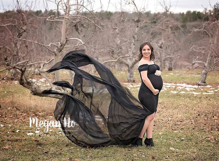 beautiful mama to be in black flowing dress holding baby bump